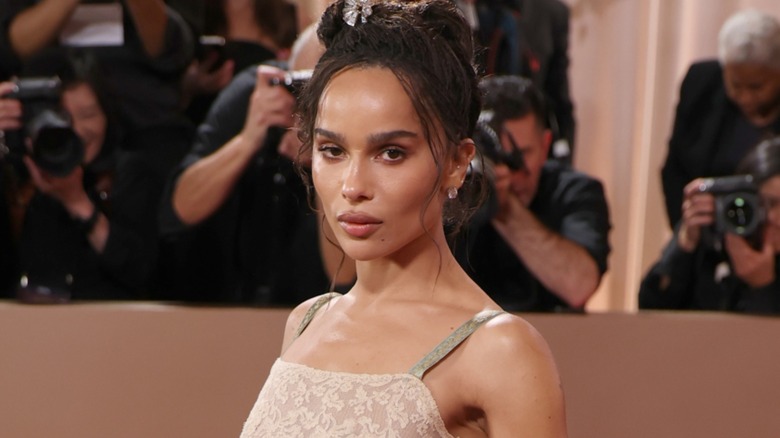 Zoë Kravitz with a neutral expression on the red carpet standing in front of photographers