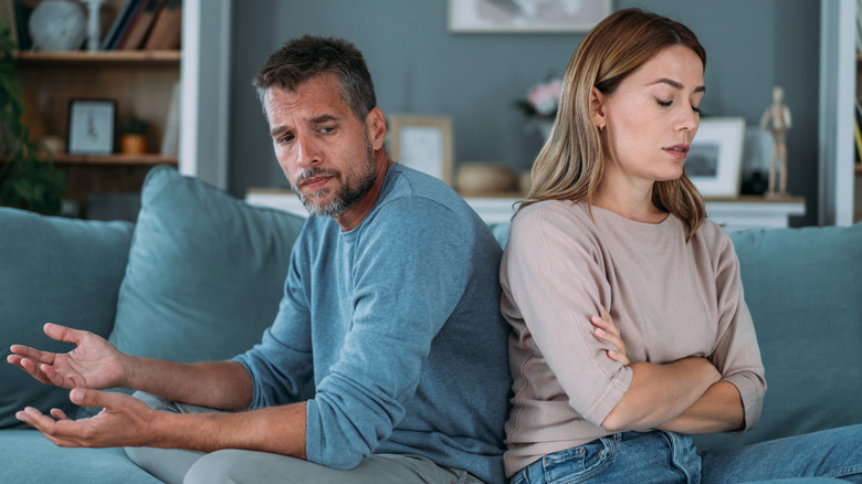 Shot of a young couple having a disagreement at home. Couple ignoring each other while sitting back to back on the couch.