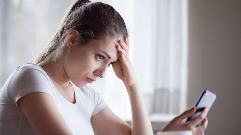 stressed lady looks at smartphone