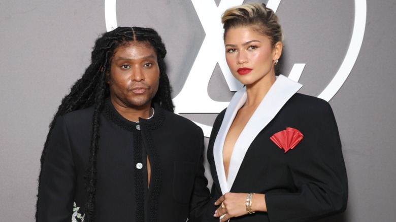 Law Roach and Zendaya posing in front of a gray background