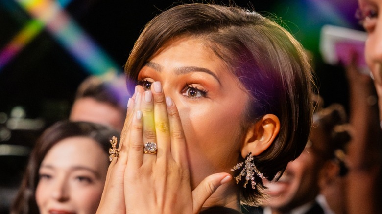 Zendaya with her hands over her mouth, showing her engagement ring and possible wedding ring, at the 2026 Oscars