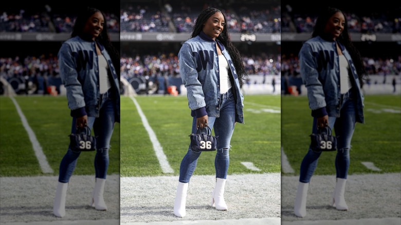 Simone Biles smiling at an NFL game while wearing skinny jeans and a denim jacket