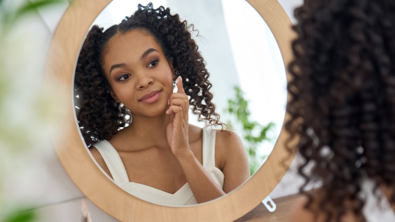 Woman applying skincare at mirror
