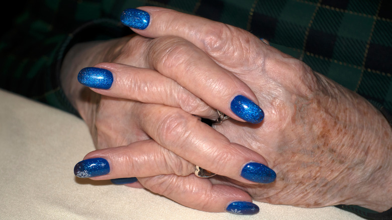 An older woman is painting her nails.