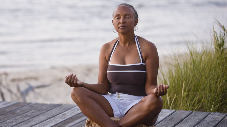 Woman meditating on wooden dock