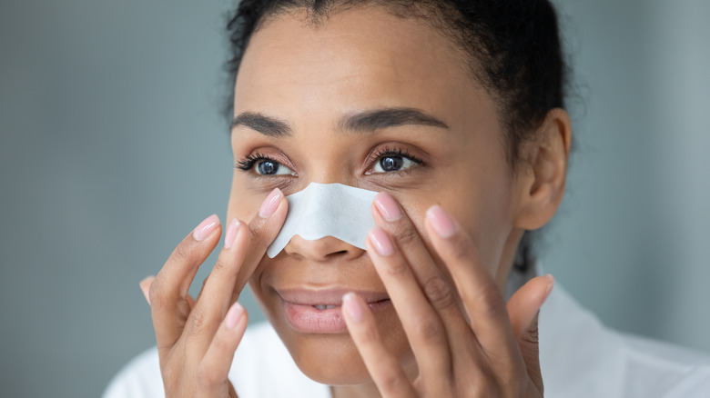 A woman applying a pore strip on her nose