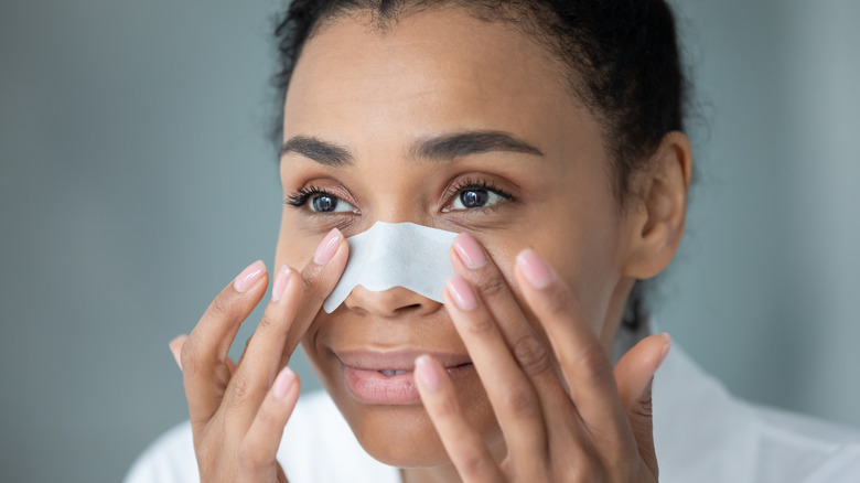 A woman applying a pore strip on her nose