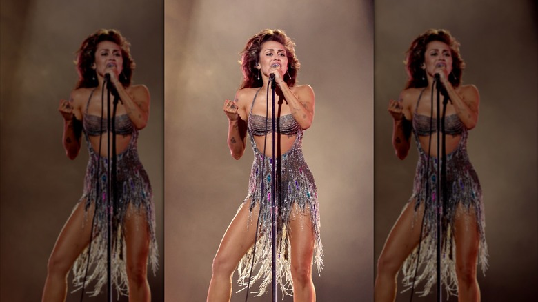 Miley Cyrus performing in a silver fringe dress