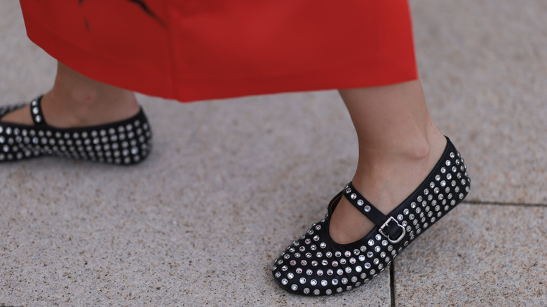 A woman in a red skirt with bedazzled ballet flats on