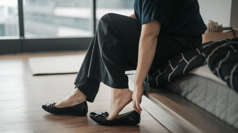 A woman in denim and blue glove flats standing outside