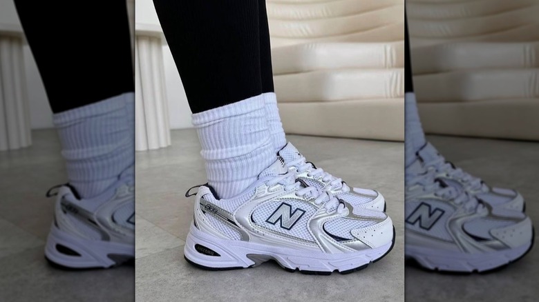 A woman wearing white sneakers with white socks over black leggings