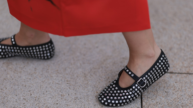 A woman in a red skirt with bedazzled ballet flats on