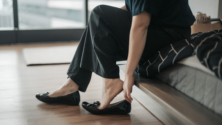 A woman in denim and blue glove flats standing outside