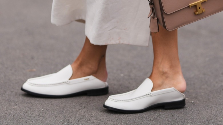 A woman wearing a white pair of blackless loafers