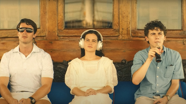 Three young people sitting in a row on a boat