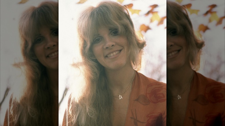 Stevie Nicks smiling at the camera during an outdoor photo shoot in 1975