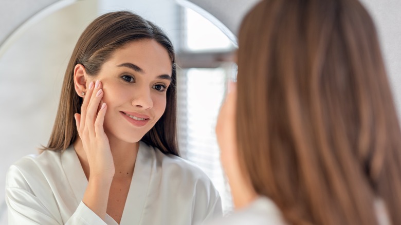 Woman touching face in mirror