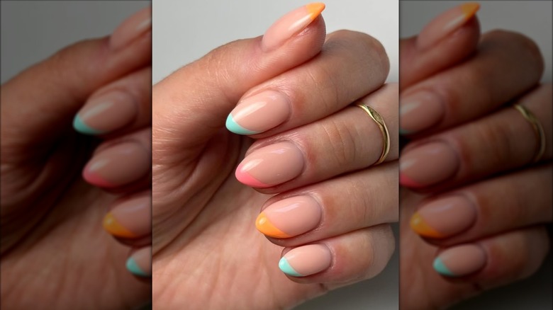 Hands with a French manicure with different colored tips