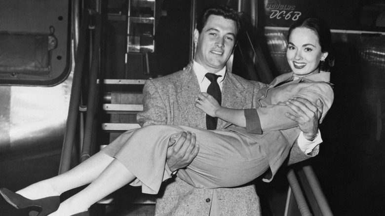 Ann Blyth being carried off a plane by actor Rock Hudson