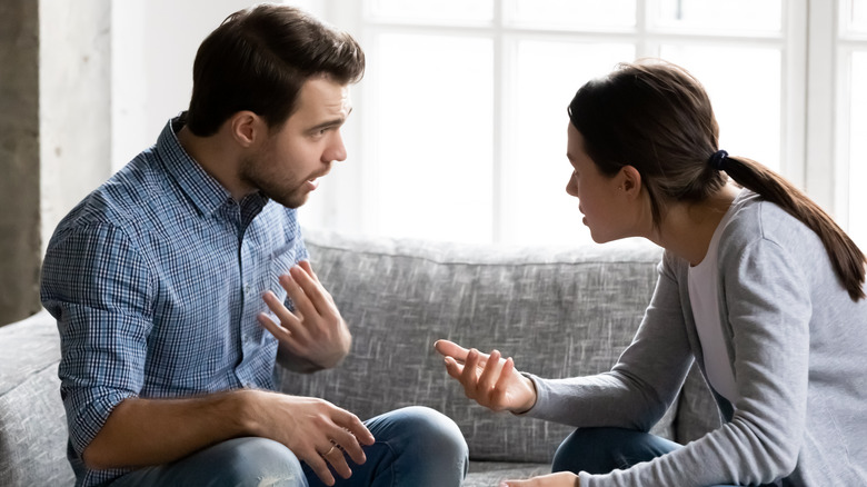 Couple arguing while seated on sofa