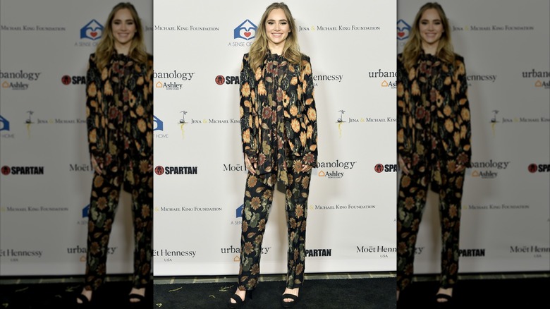 Suki Waterhouse smiling at A Sense Of Home's First Ever Annual Gala while wearing a floral-patterned outfit