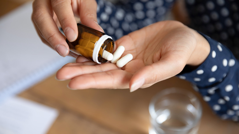 Woman pouring capsules from a bottle onto her hand
