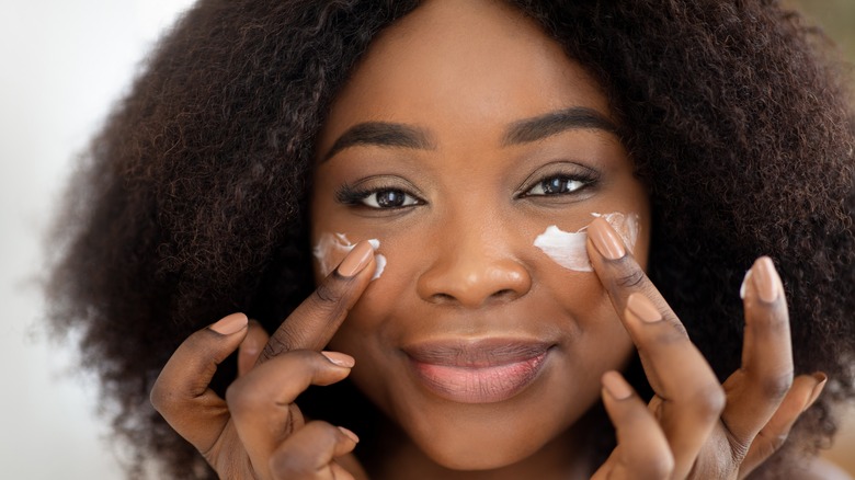 Woman smiling while applying sunscreen