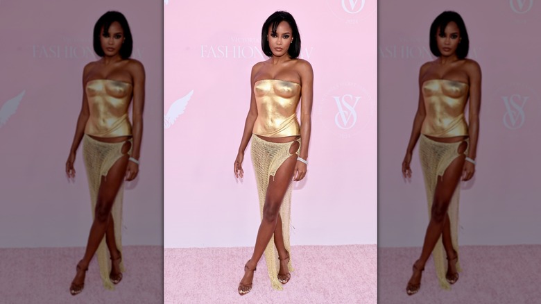 Ciara Miller poses wearing a gold corset and sarong-style skirt