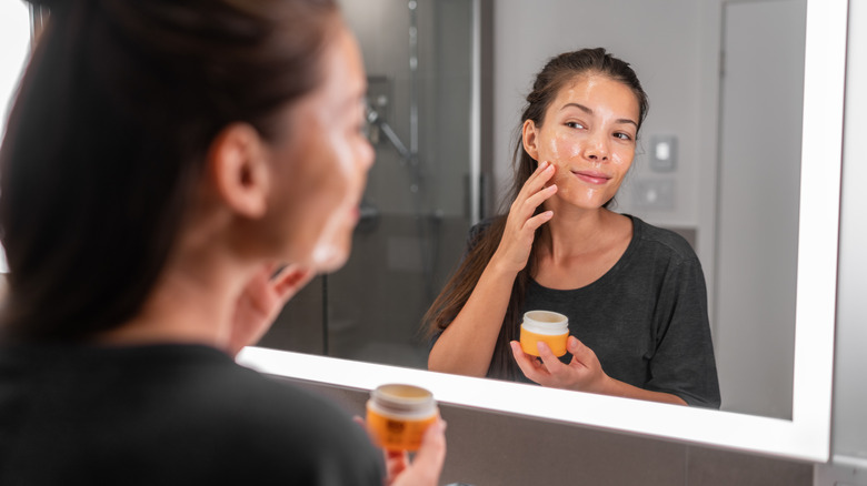 woman applying lotion in mirror