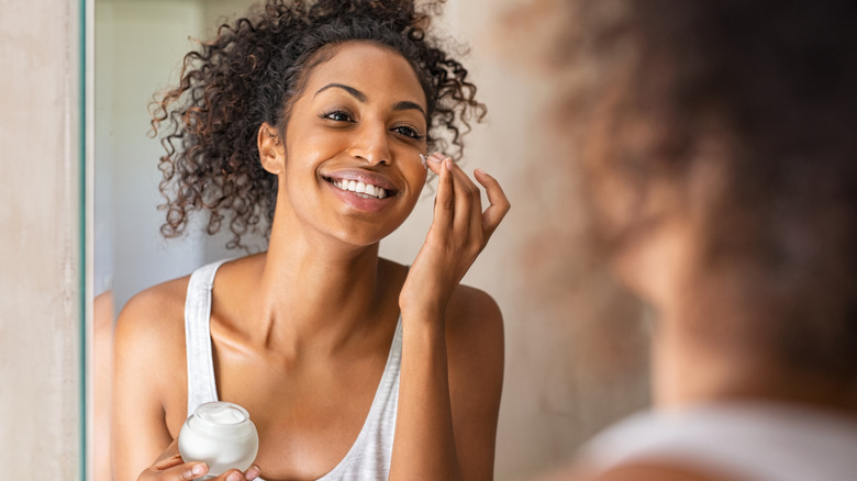 woman applying cream in mirror