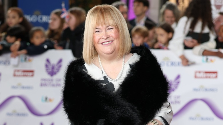 Susan Boyle smiling on the red carpet in 2025 with a blond bob