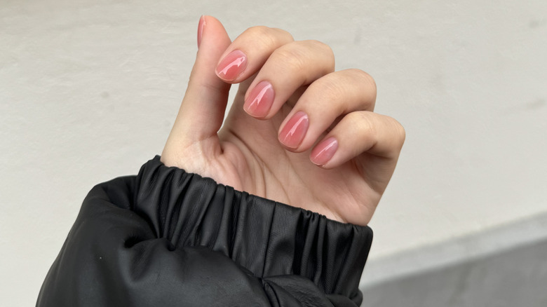 A woman's hand with pink syrup nails
