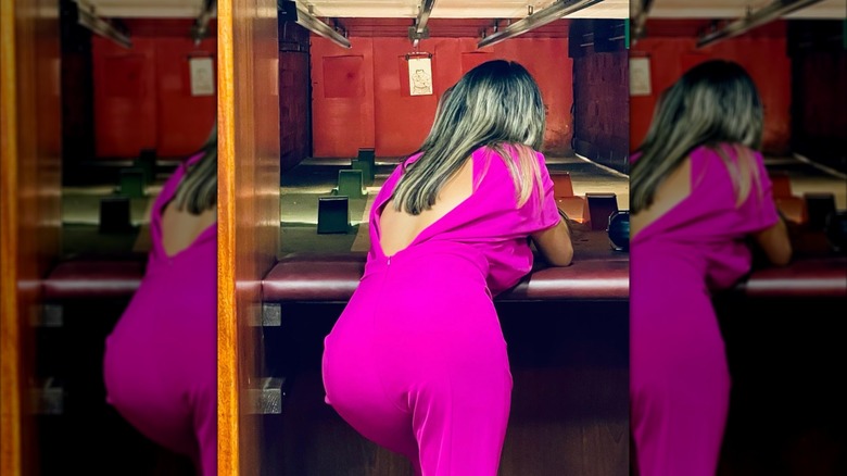 Alina Habba bent over at a shooting range in a pink jumpsuit