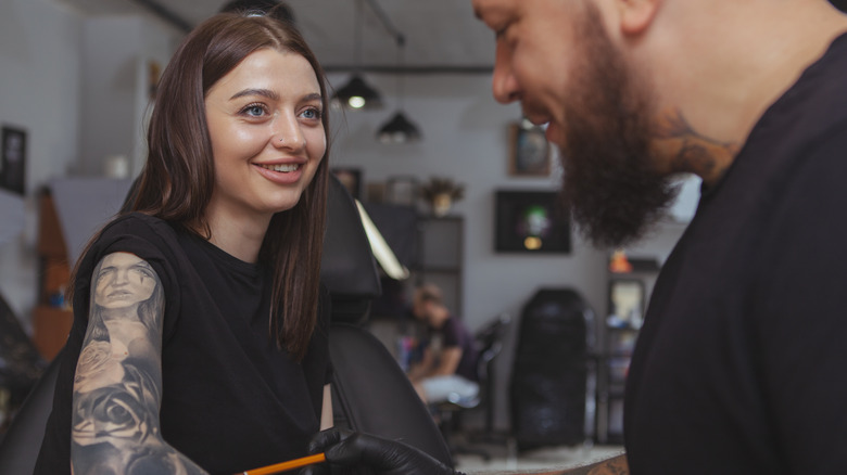 Woman smiles while getting tattoo on her arm