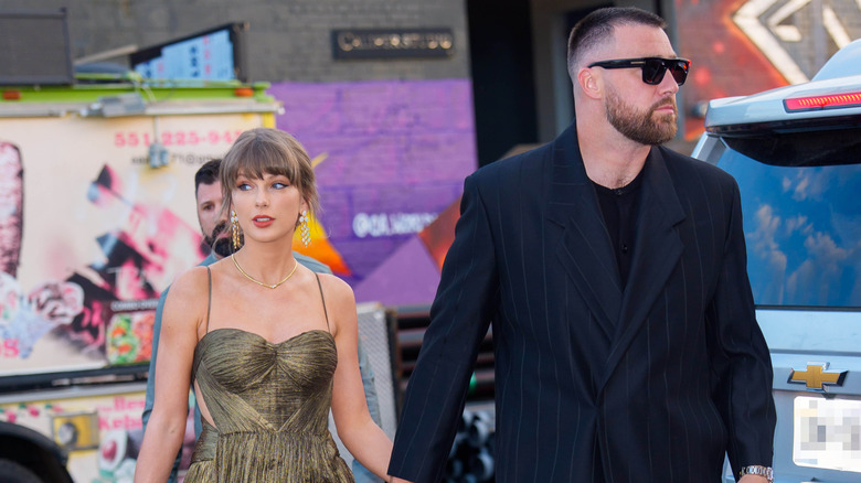 Travis Kelce and Taylor Swift walking in formal clothing