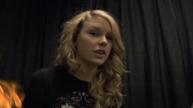 A still of curly-haired Taylor Swift working behind-the-scenes for the music video of "Picture to Burn"
