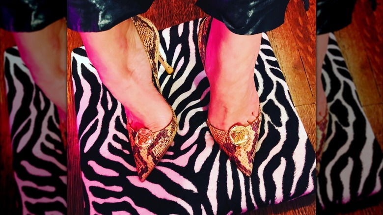 A close up of Juno Temple's shoes in snake skin on top of a zebra print pillow