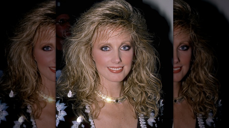 Morgan Fairchild with blond hair and gold choker necklace