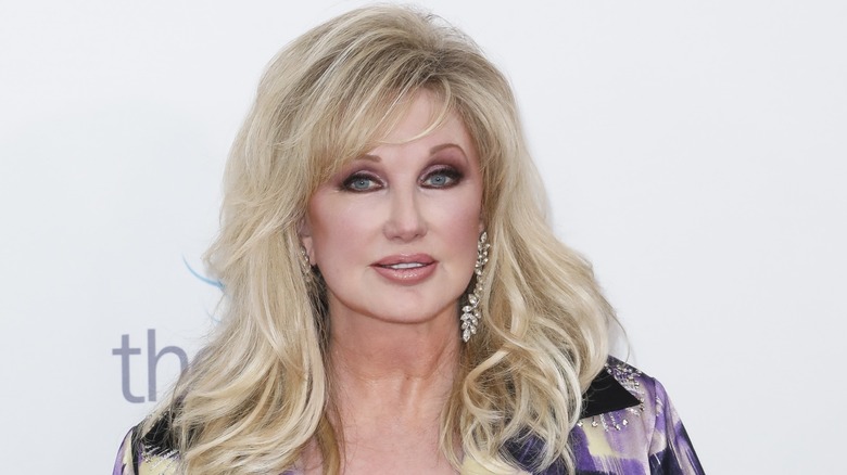 Morgan Fairchild with blond hair and purple and silver blazer