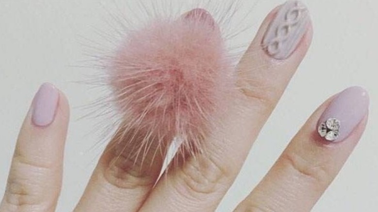 A pink manicure with a large pompom from 2016