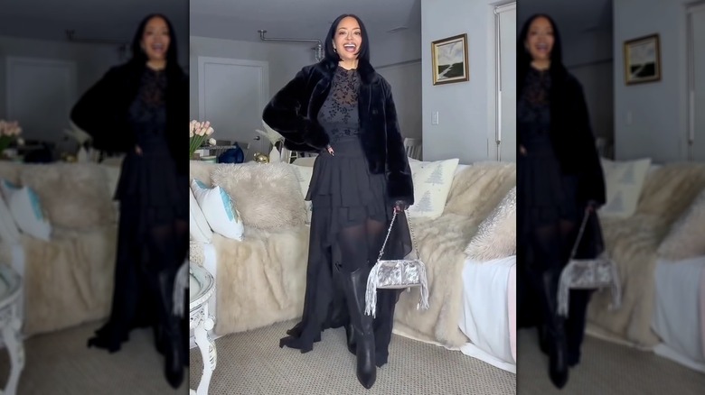 A woman holding a silver bag with a black outfit