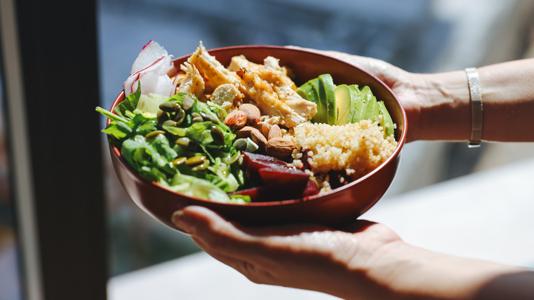 Hands holding bowl of salad