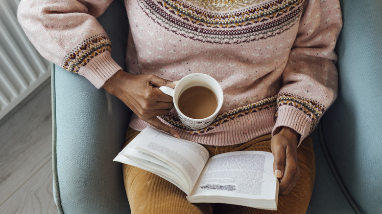 Bird's eye view of woman reading a book with a cup of coffee