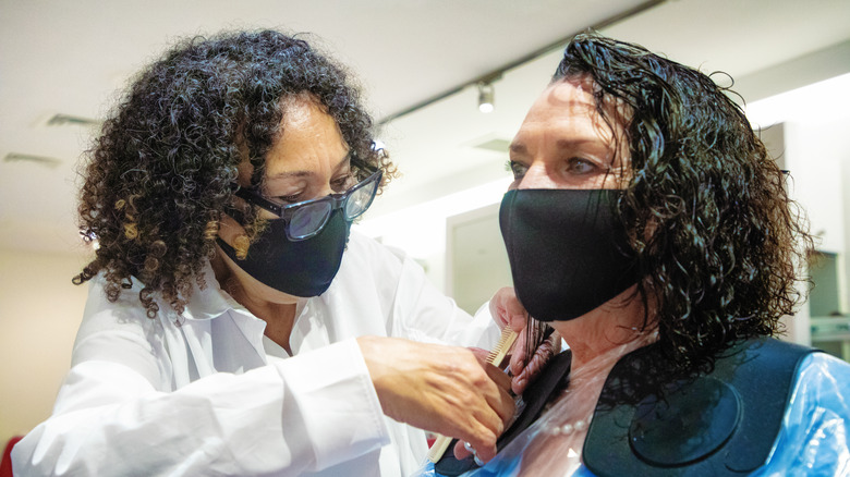 Stylist trimming client's damp hair