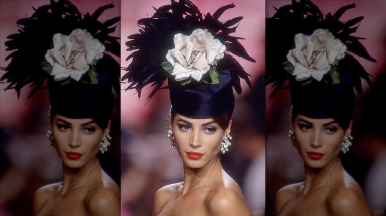 Christy Turlington poses wearing red lipstick and a floral headpiece