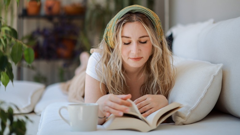 A woman laying on her front while reading a book