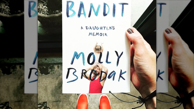 A hand holding up a copy of the book "Bandit" by Molly Brodak