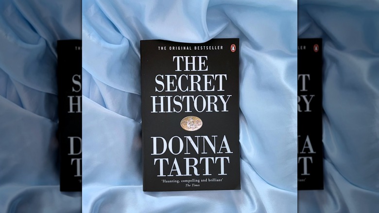 A copy of the novel "The Secret History" lying on a blue silk sheet