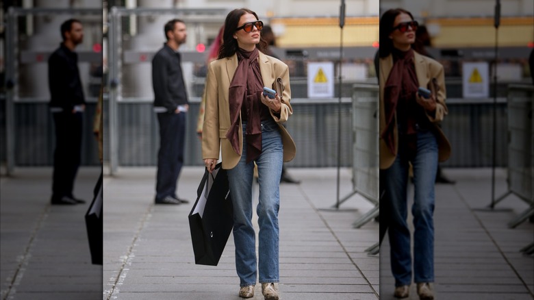 Woman wearing a tan blazer walking in straight-legged jeans