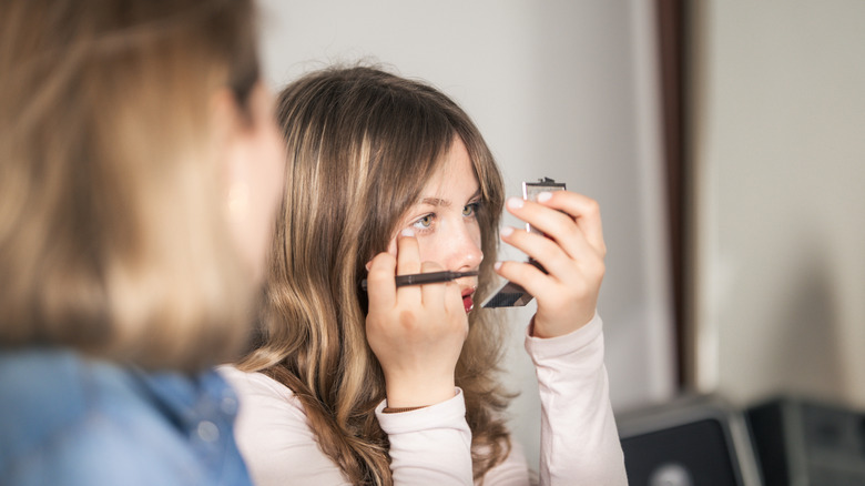 Young woman applying eyeliner, preparing for a day or event